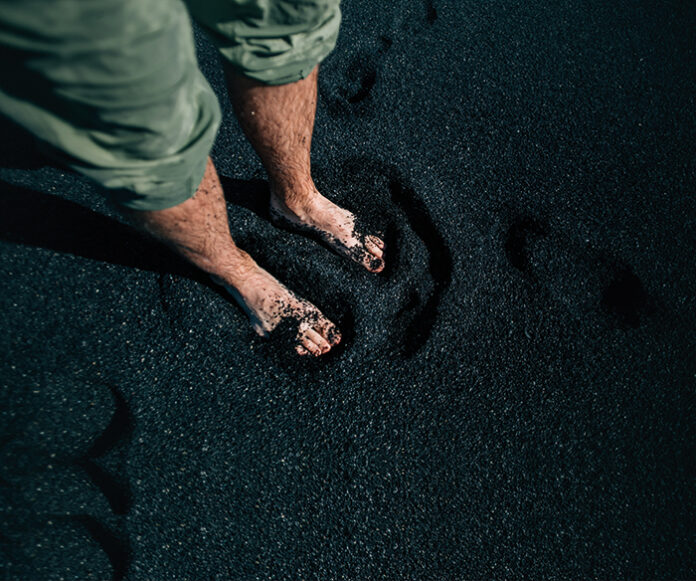 Man barefoot on black sand beach in iceland